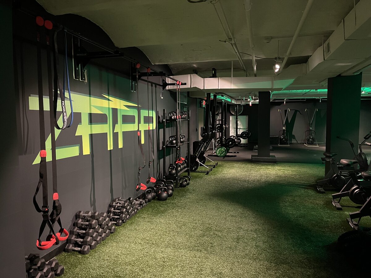 Open turf lane with suspension straps, kettlebells, and dumbbells